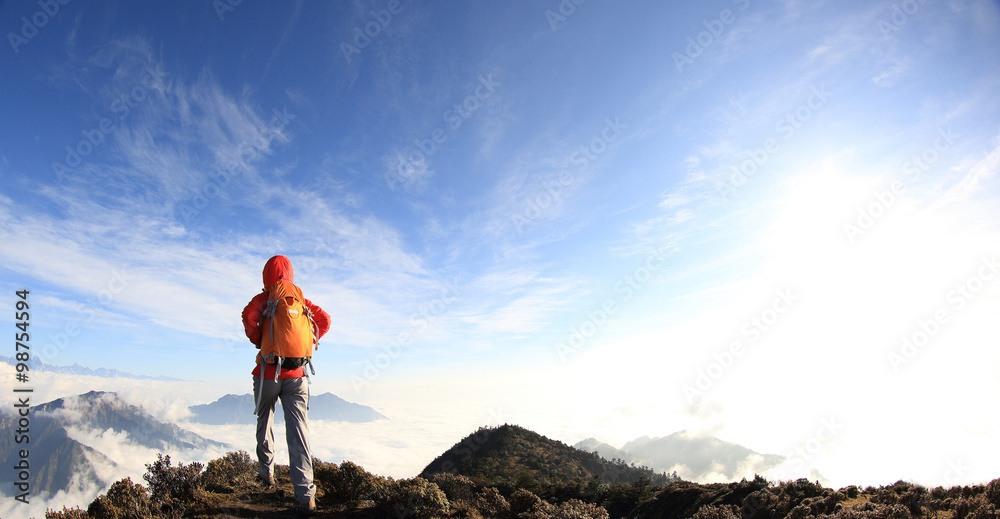 young woman backpacker hiking on mountain peak