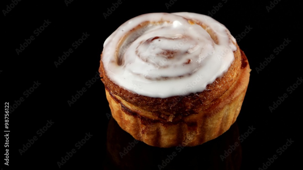 Fresh cinnamon roll coated in icing for breakfast
