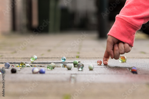 Child playing with marbles on yhe sidewalk.
old-fashioned toys still in use today. photo