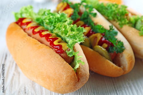 Delicious hot-dogs on white wooden background, close up