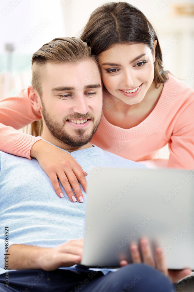 Happy couple working on laptop in a room Happy couple working on laptop in a room