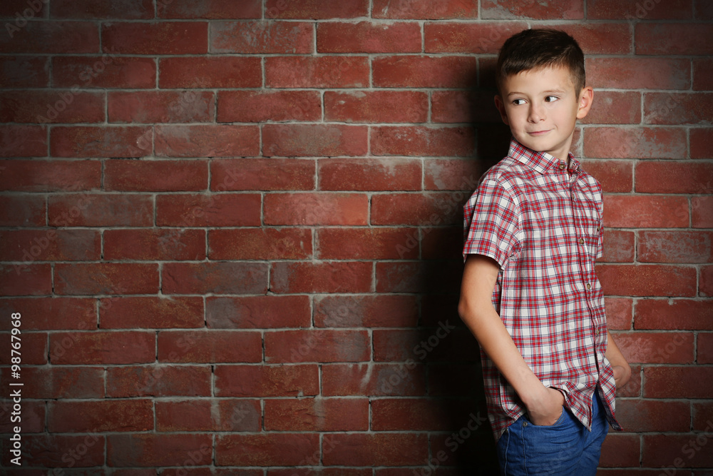 Cute little boy on brick wall background. Kids fashion concept Cute little boy on brick wall background. Kids fashion concept