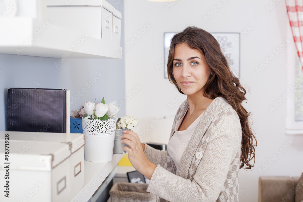 Beautiful woman arranging flowers and decorating her living room Shallow depth of field. Beautiful woman arranging flowers and decorating her living room Shallow depth of field.
