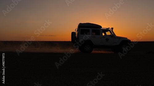 driving off-road car in the sahara desert at sunset