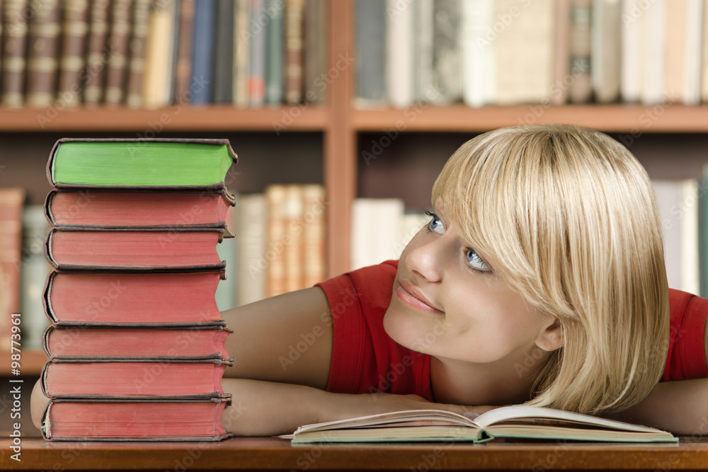 Female student with elbows on the table looking at books Female student with elbows on the table looking at books