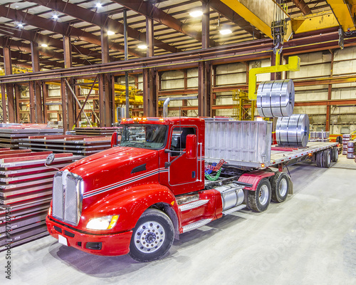 Red truck being loaded in the bay under ceiling lights