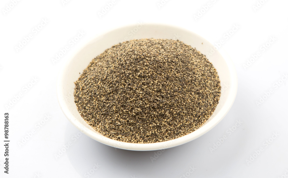 Black pepper powder in white bowl over white background Black pepper powder in white bowl over white background