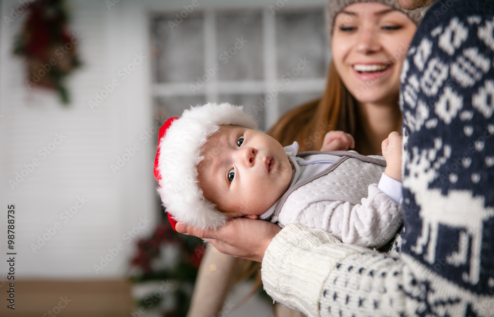 Little baby boy in father's hands, young mother looking at son with joy Little baby boy in father's hands, young mother looking at son with joy