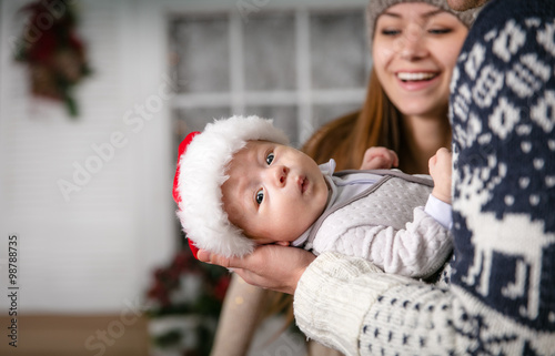 Little baby boy in father's hands, young mother looking at son with joy