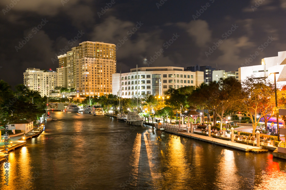 Night view of New River with Riverwalk promenade highrise condominium buildings and yachts in Fort Lauderdale, Florida, USA