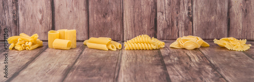 Assortment of different shape pastas over wooden background photo