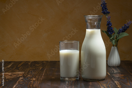 Milk bottle and milk glass put on wooden table.