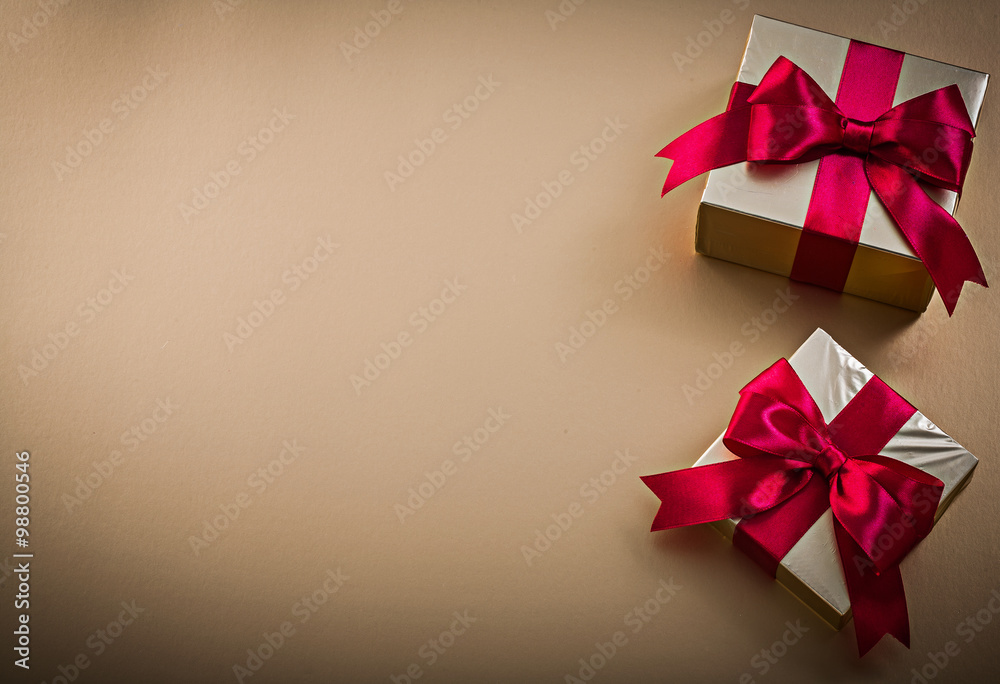 Present boxes with tied ribbons on golden surface holidays conce Present boxes with tied ribbons on golden surface holidays conce