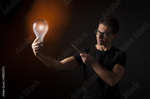 Ragazzo indica una lampadina accesa che tiene in mano: concetto di idea, ispirazione, creatività, innovazione