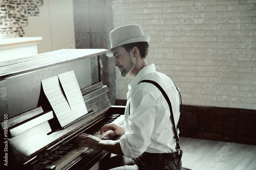 Canvas Print Handsome young man in hat making piano music