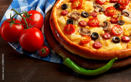 Delicious pizza with vegetables and meat on blue napkin, close-up