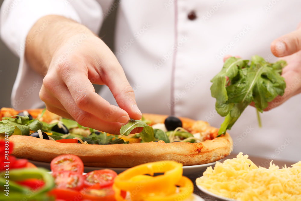 Cook making delicious pizza at the restaurant, close-up