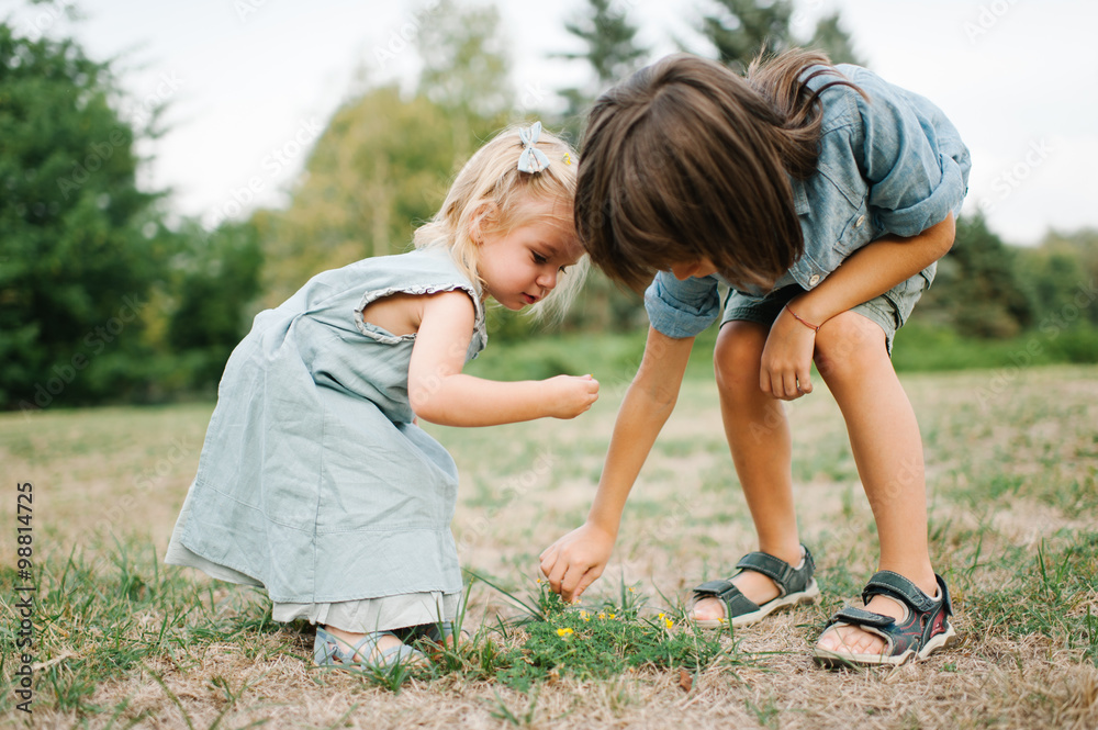 Cute portrait of young brother and sister playing in the park on grass Cute portrait of young brother and sister playing in the park on grass
