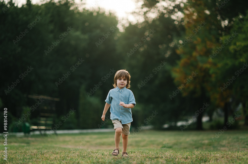 Boy running on grass in park on summer sunset afternoon and playing Boy running on grass in park on summer sunset afternoon and playing
