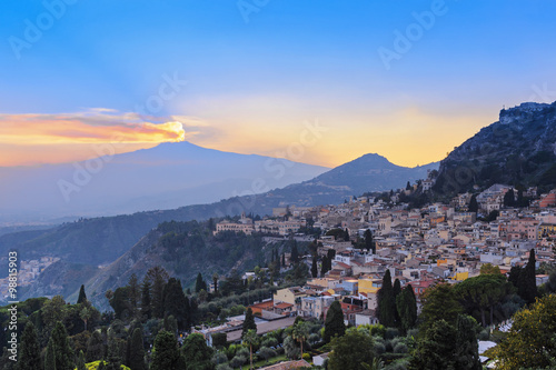 View of the city of Taormina and the active volcano Etna at suns