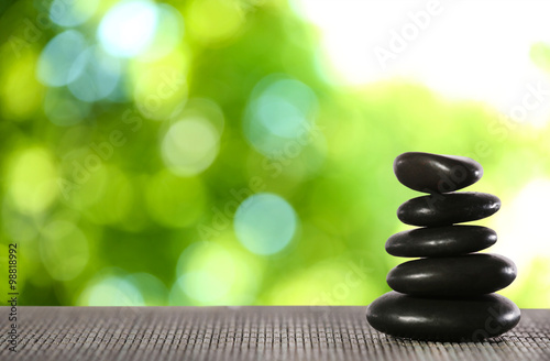 Stack of spa stones on bamboo mat against blurred nature background