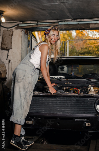 young blonde girl with long hair is an auto mechanic in the garage with a  lot of tools on the shelves holding wrenches Stock Photo | Adobe Stock