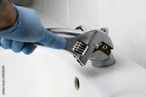 Tap fixing spanner / Man fixing tap in a bathroom with a spanner.