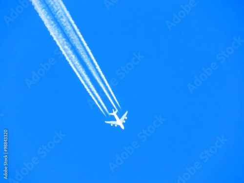 Airplane with chemtrails on blue sky