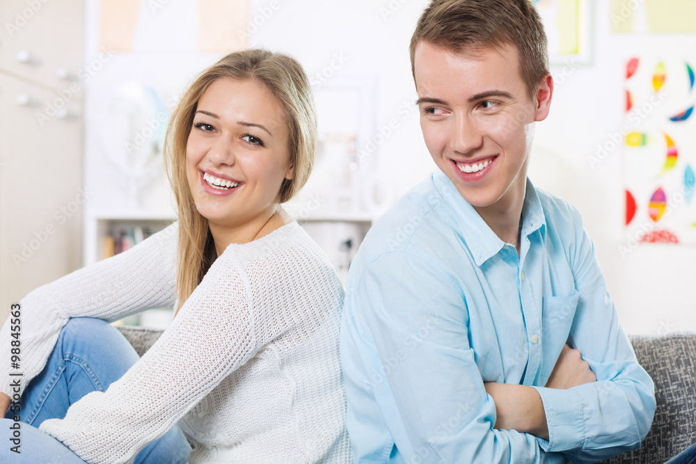 Young couple sitting on the living room couch back to back Young couple sitting on the living room couch back to back