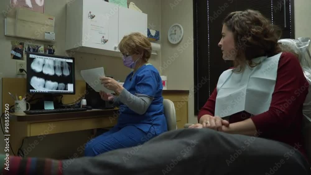 Dentist or dental hygienist discusses dental x-ray exam results with patient