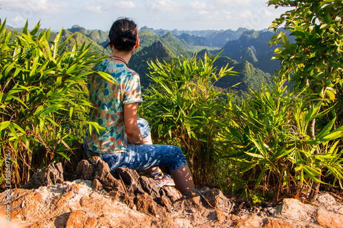 Woman sitting on top of the mountain and looking at the mountains. Vietnam.