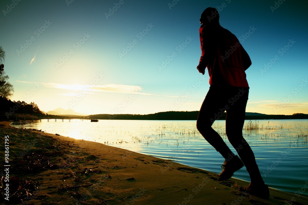 Running man. Male runner jogging during the sunrise on sandy beach