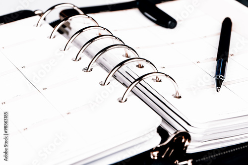Personal organizer or planner with pen on white background