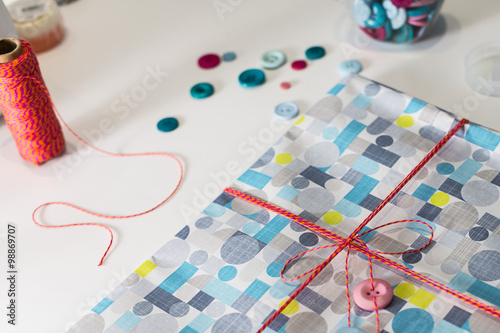 Gift present con colorful wrap paper and decoration buttons on a white table