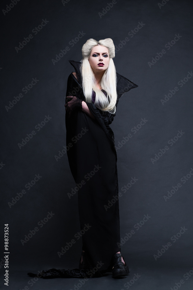Beautiful blonde girl vampire standing. Studio photo with black background. Beautiful blonde girl vampire standing. Studio photo with black background.