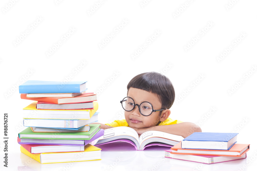 Cute boy is reading a book with a stack of books.