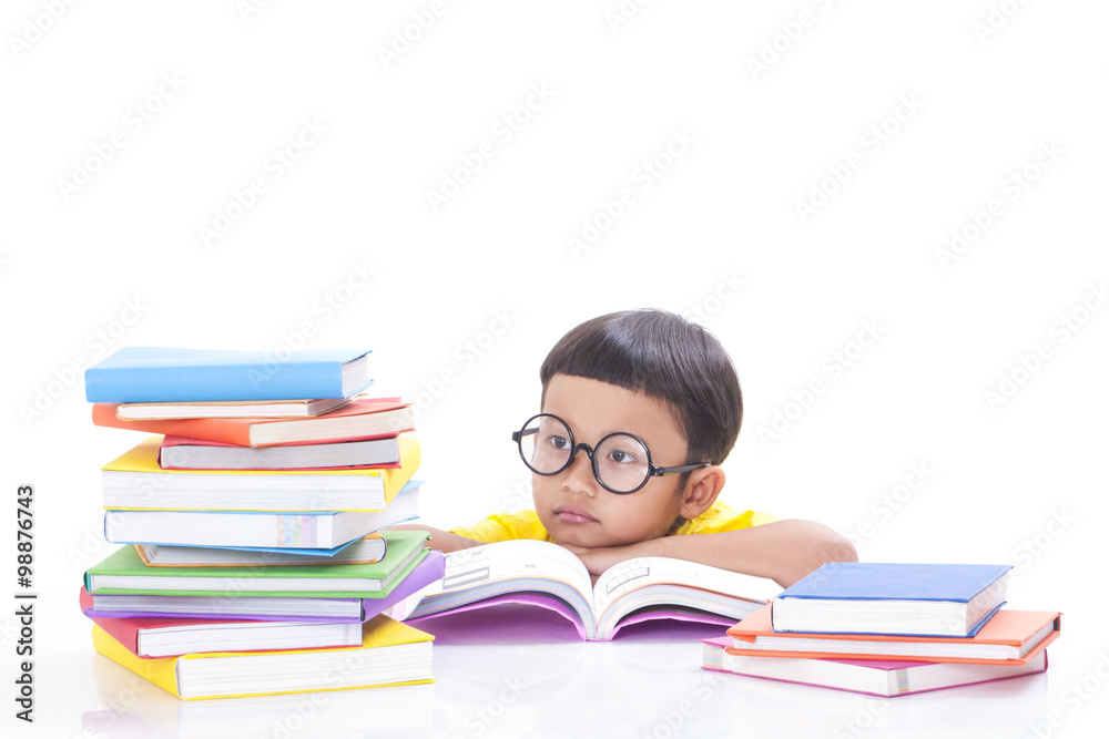 Cute little boy is reading a book with a stack of books.