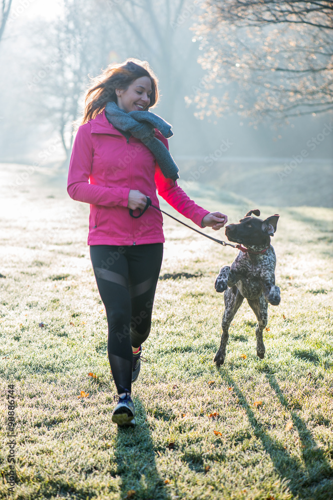 Runner woman and her cute German pointer dog running together outdoor at the beautiful park. Runner woman and her cute German pointer dog running together outdoor at the beautiful park.