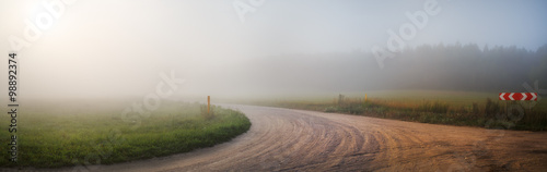 Gravel road in the fog. Turn of gravel road. Rural landscape. Panoramic shot. Toned image. © Veresovich