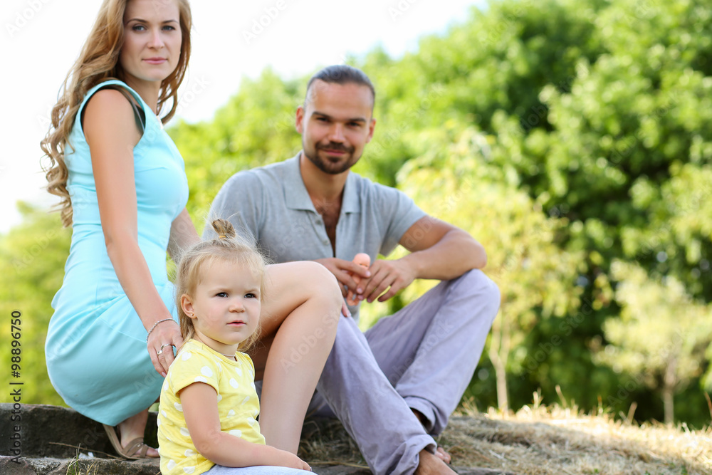 Fototapeta premium Young parents with daughter on picnic outdoor at beautiful sunny