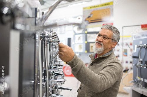 Fotografie Senior man choosing a bathroom/kitchen tap in a home furnishings