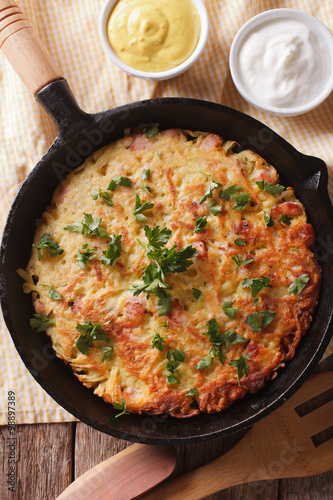 Potato pancakes with herbs close-up in a frying pan. vertical top view 