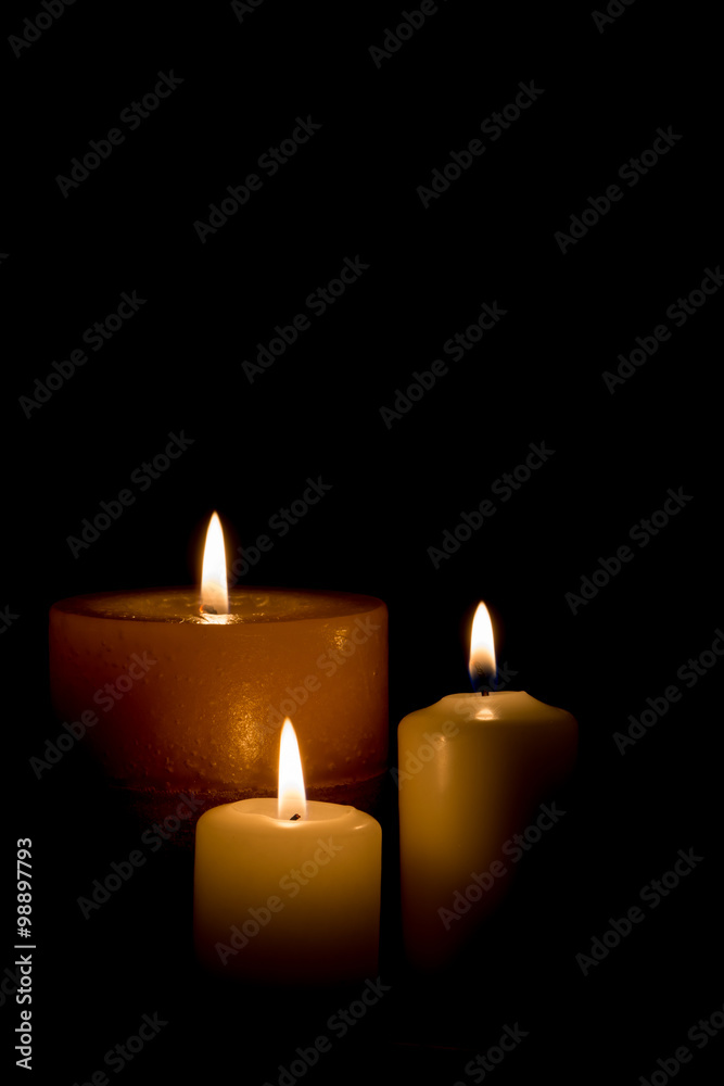Three burning candles isolated on black background. 