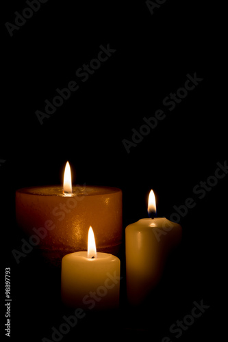 Three burning candles isolated on black background. 