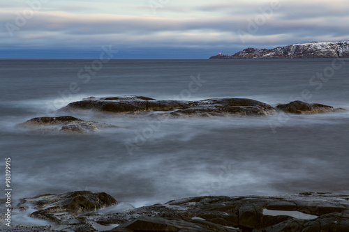 Stone beach and the lighthouse on the cape. Barencevo sea. Kola Peninsula. Murmansk region. Russia.