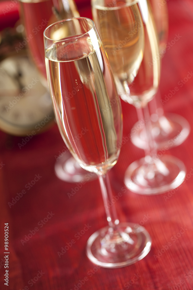 Glasses of champagne and alarm clock on red background Glasses of champagne and alarm clock on red background