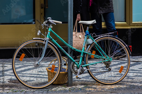 Bicycle parked on a street with food's basket.