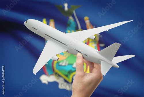 Airplane in hand with US state flag on background - New York