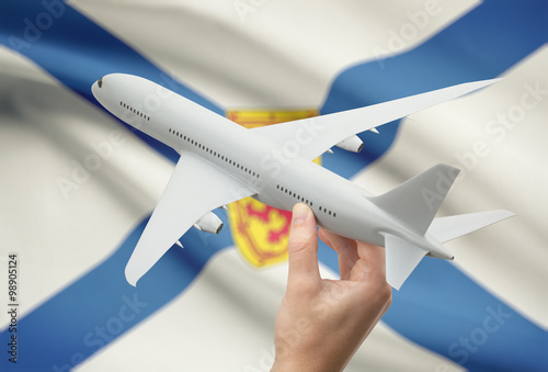 Airplane in hand with Canadian province flag on background - Nova Scotia