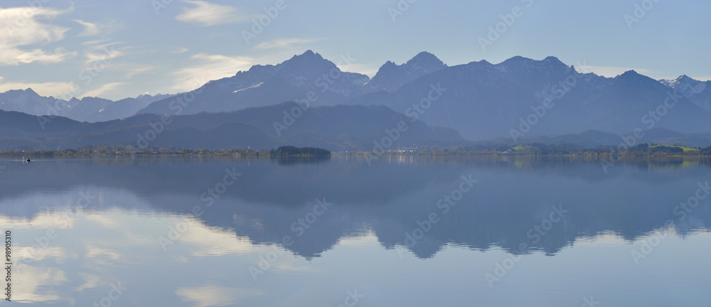 Panorama Landschaft in Bayern mit Spiegelung der Alpen im Forggensee im Allgäu